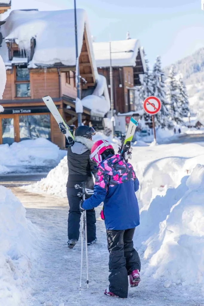 Enfants qui portent leur skis sur l'épaule et qui marchent dans les rues enneigées
