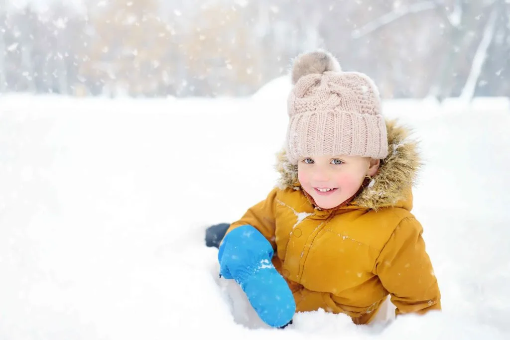 Enfant dans la neige avec un bonnet et des moufles