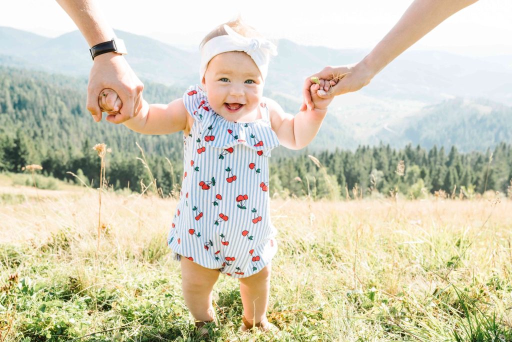 Bébé qui marche dans l'herbe en souriant