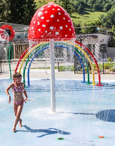 Trois enfants s'amusent avec des jeux aquatiques en forme de fleurs et de champignons à la piscine