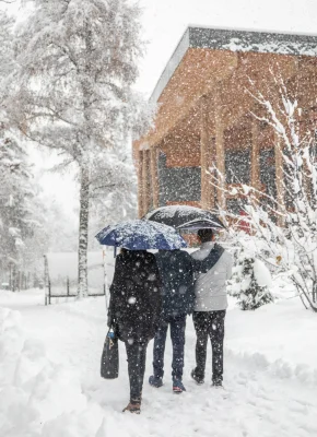 Trois personnes marchant joyeusement dans la neige, entourées d'un paysage hivernal paisible.