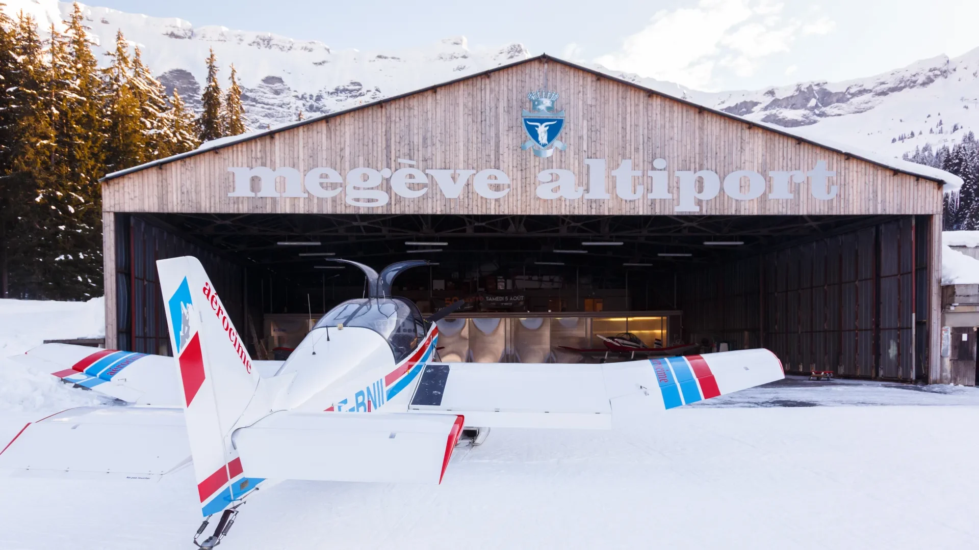 avion stationné devant l'altiport de megève dans la neige