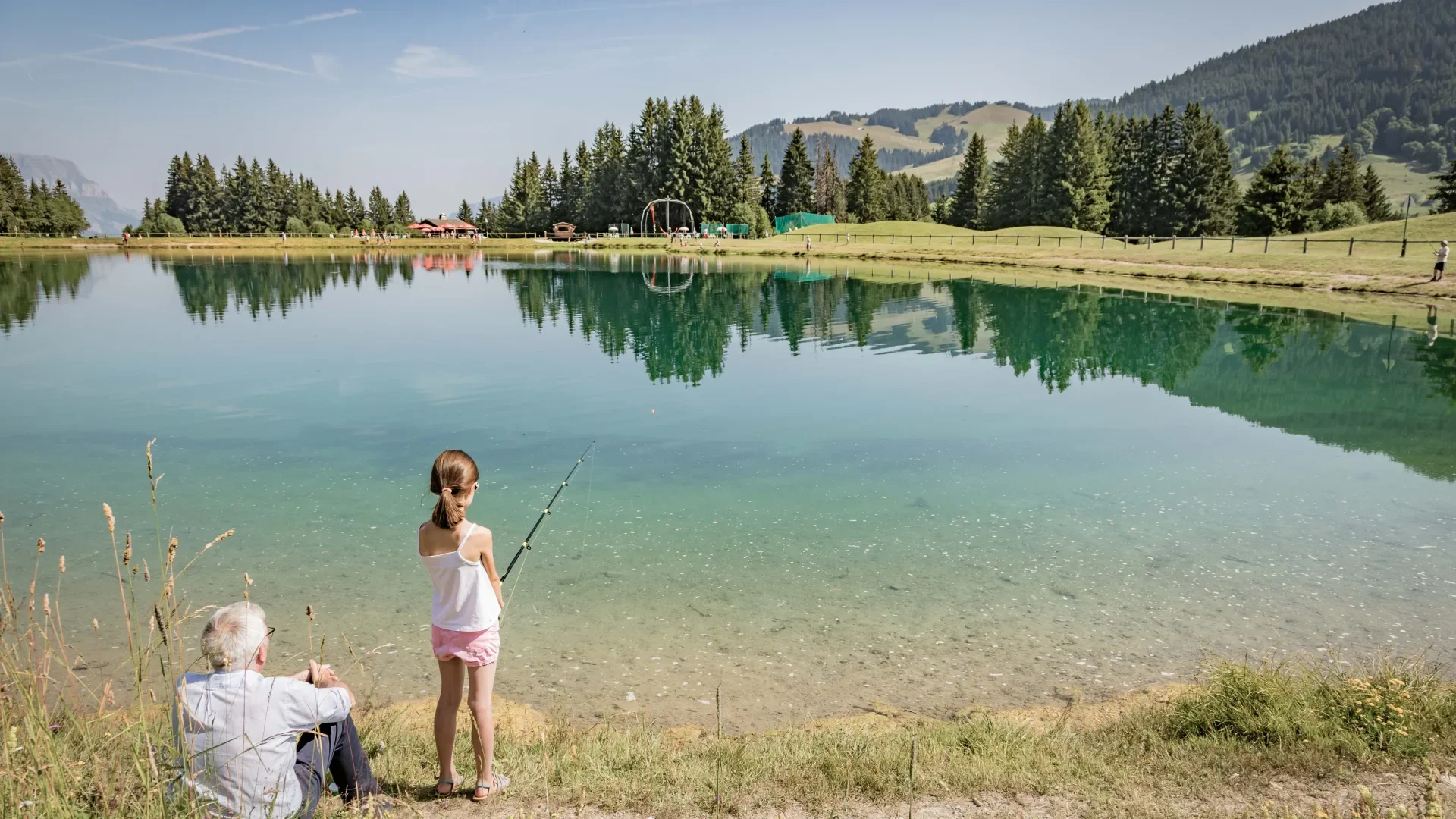grand père et sa petite fille qui pèche dans un lac à megève