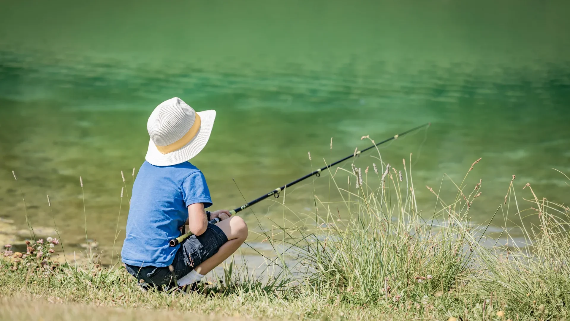 jeune garçon avec un chapeau qui pêche au lac à megève
