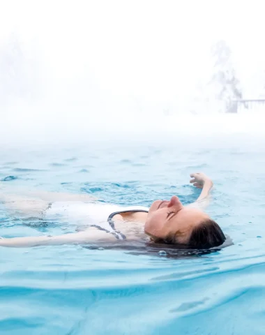 femme allongée qui flotte dans l'eau de la balnéoforme de megève dans une eau chaude en hiver