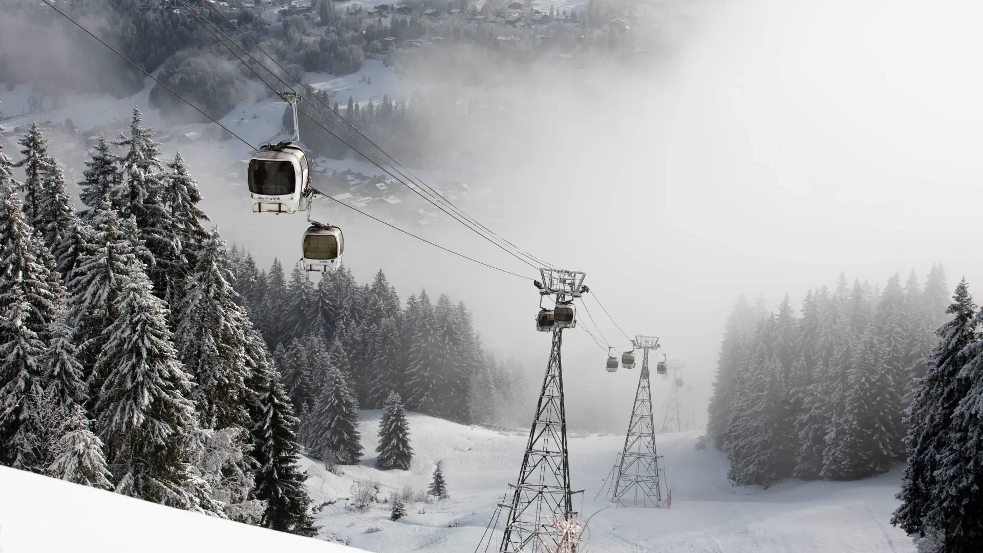 cabines de remontées mécaniques dans le brouillard avec un paysage enneigé