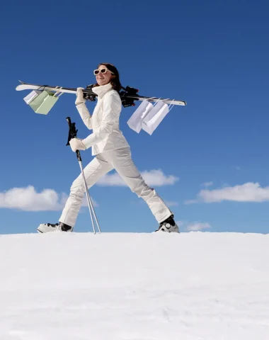 Uma pessoa caminhando na neve em Megève sob um céu azul.