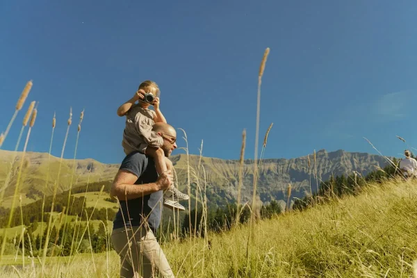 Homme portant sa fille sur le dos en randonnée